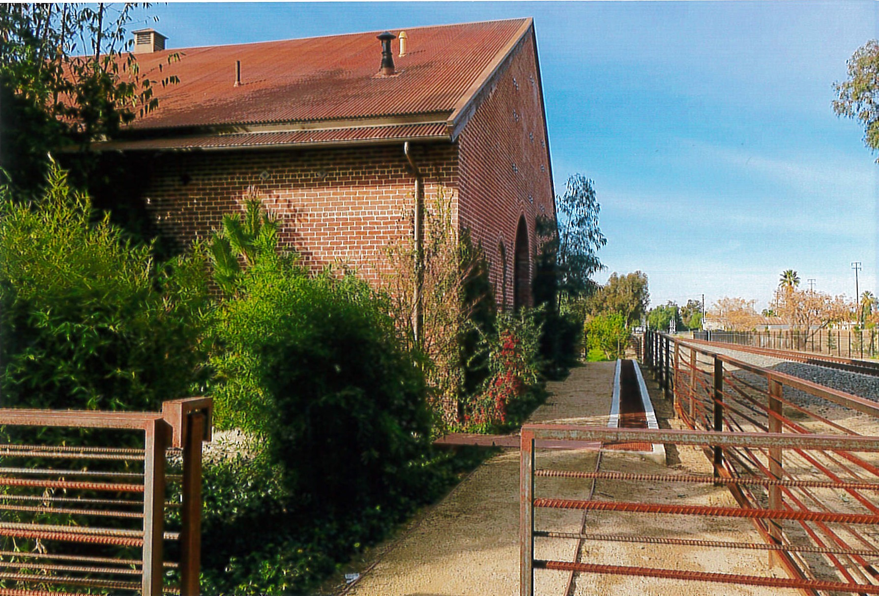 North and east facades, new pedestrian pathway and railing, railroad tracks 